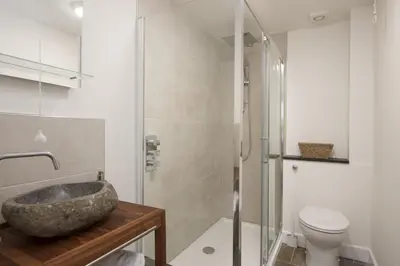 a bathroom with a stone sink and a toilet at Greenfields Coach House - Balcony with stunning ocean view in Marazion