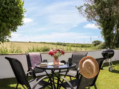 a patio table with chairs and a vase of flowers at Summerhayes in Redruth