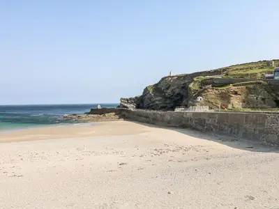 a beach with a retaining wall next to the ocean at Summerhayes in Redruth