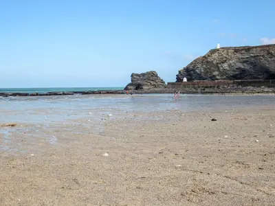 a sandy beach with people standing in the water at Summerhayes in Redruth