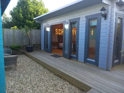 a small house with a wooden deck at Sandy Toes Accommodation in Par