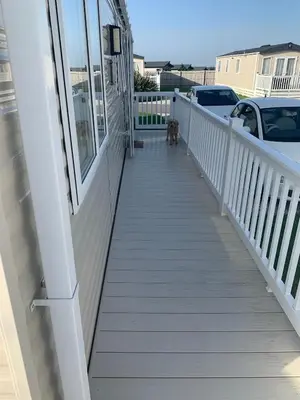 a white porch with a dog standing on it at Bude 13 in Cubert