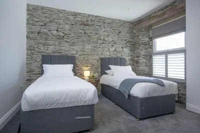 two beds in a bedroom with a stone wall at Ocean View, Newquay - Free WiFi & Parking - Sea Views in Newquay