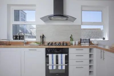 a kitchen with white cabinets and a stove top oven at Ocean View, Newquay - Free WiFi & Parking - Sea Views in Newquay