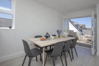 a dining room with a wooden table and chairs at Ocean View, Newquay - Free WiFi & Parking - Sea Views in Newquay