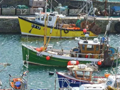 three boats are docked in the water in a harbor at Rose Cottage in St Austell