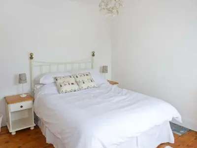 a white bed with two pillows on it in a bedroom at Rose Cottage in St Austell
