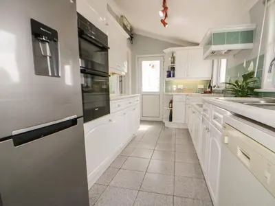 a large white kitchen with white cabinets and appliances at Robin Hill in St Austell