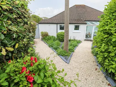 a garden with a cross in front of a house at Robin Hill in St Austell