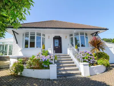 a white house with flowers in front of it at Robin Hill in St Austell