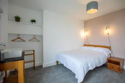 a bedroom with a bed and a desk and a sink at OA Surf Club in Bude