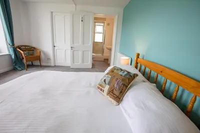 a bedroom with a large white bed with a pillow on it at OA Surf Club in Bude