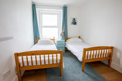 two beds in a room with a window at OA Surf Club in Bude