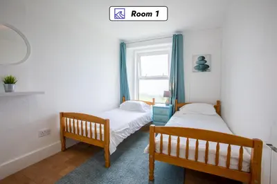 two beds in a room with a window at OA Surf Club in Bude