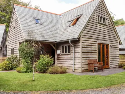 a house with a gambrel roof with a bench in a yard at Bybrook Lodge in Camelford