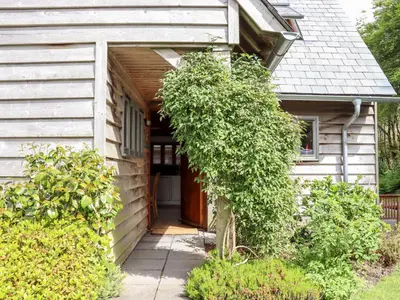 a small white house with a wooden door at Bybrook Lodge in Camelford