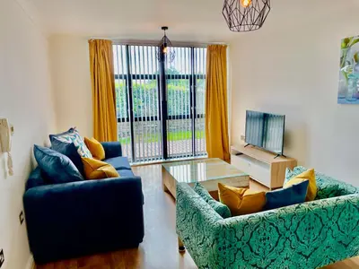 a living room with two blue couches and a television at Pochin House Collections in St Austell