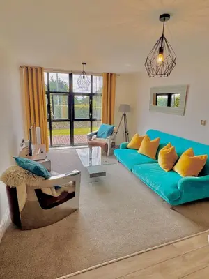 a living room with a blue couch and yellow pillows at Pochin House Collections in St Austell