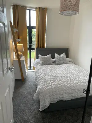 a bedroom with a bed with white sheets and a window at Pochin House Collections in St Austell