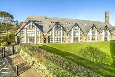 an exterior view of a large building with a green lawn at Pochin House Collections in St Austell