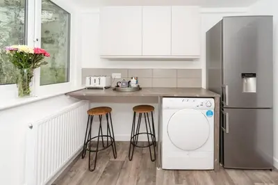 a kitchen with a refrigerator and a counter with stools at Large House in Looe, Near Beach and Bars with Great Views, Free Parking and Free Access to a Nearby Indoor Swimming Pool in Looe