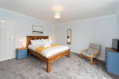 a bedroom with a bed and a chair and a television at Large House in Looe, Near Beach and Bars with Great Views, Free Parking and Free Access to a Nearby Indoor Swimming Pool in Looe