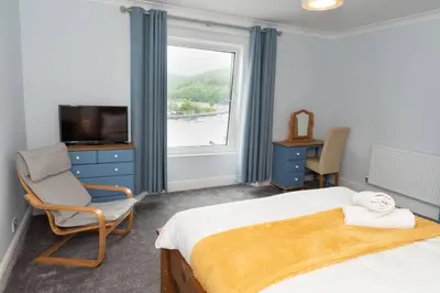 a bedroom with a bed and a chair and a window at Large House in Looe, Near Beach and Bars with Great Views, Free Parking and Free Access to a Nearby Indoor Swimming Pool in Looe