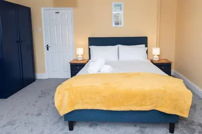 a bedroom with a large bed with a yellow blanket on it at Large House in Looe, Near Beach and Bars with Great Views, Free Parking and Free Access to a Nearby Indoor Swimming Pool in Looe