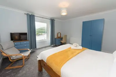 a bedroom with a bed and a chair and a television at Large House in Looe, Near Beach and Bars with Great Views, Free Parking and Free Access to a Nearby Indoor Swimming Pool in Looe