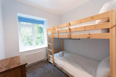 a bedroom with two bunk beds and a window at Large House in Looe, Near Beach and Bars with Great Views, Free Parking and Free Access to a Nearby Indoor Swimming Pool in Looe