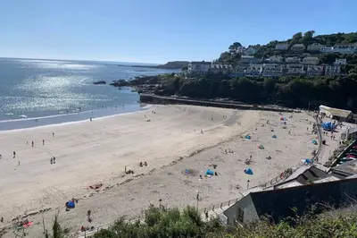 a group of people on a beach near the water at Large House in Looe, Near Beach and Bars with Great Views, Free Parking and Free Access to a Nearby Indoor Swimming Pool in Looe
