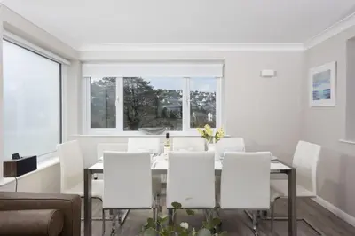 a white dining room with a glass table and white chairs at Fairsky - Sea Views and Allocated Parking in Carbis Bay