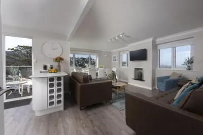 a living room with couches and a kitchen and a living room with a table at Fairsky - Sea Views and Allocated Parking in Carbis Bay