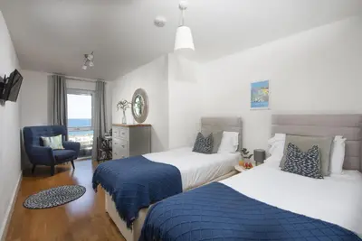 a hotel room with two beds and a chair at Ocean lookout & explore the coast in Newquay