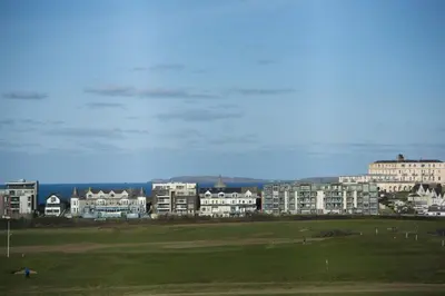 a view of a golf course with buildings in the background at Ocean lookout & explore the coast in Newquay
