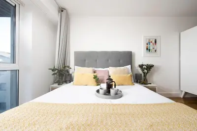 a white bedroom with a large bed with yellow pillows at Ocean lookout & explore the coast in Newquay