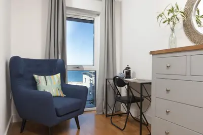 a blue chair sitting in a room with a window at Ocean lookout & explore the coast in Newquay