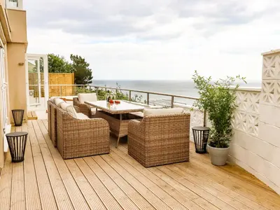 a balcony with a table and chairs and the ocean at Ocean View in Torpoint