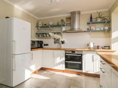 a kitchen with white cabinets and a white refrigerator at Ocean View in Torpoint