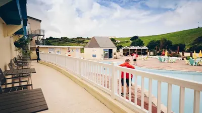 a person standing on a balcony next to a pool at NB12 Entire Caravan - Newquay in Porth