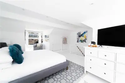 a white bedroom with a bed and a flat screen tv at St Hilary in St Ives