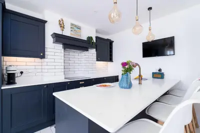 a kitchen with blue cabinets and a white counter top at St Ives House in St Ives