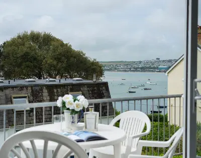a table and chairs on a balcony with a view of the water at Slipway 10 in Padstow