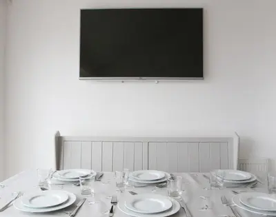 a table with plates and wine glasses and a television at Slipway 10 in Padstow