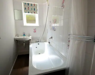 a white bathroom with a tub and a sink at Gullsway Sandpiper in Polzeath
