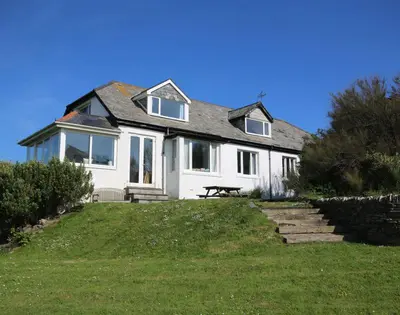 a white house with a bench in front of it at Gullsway Sandpiper in Polzeath
