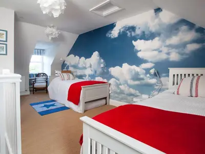 a bedroom with a blue and white clouds mural at Lowenna Manor 4 in Padstow