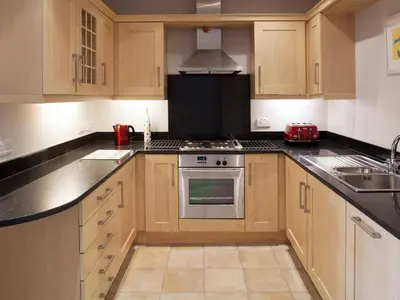 a kitchen with wooden cabinets and a stove top oven at Lowenna Manor 4 in Padstow