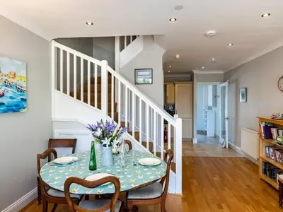 a dining room with a table and chairs and a staircase at Lowenna Manor 4 in Padstow