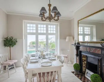a dining room with a white table and a fireplace at Folly 2 in Port Isaac